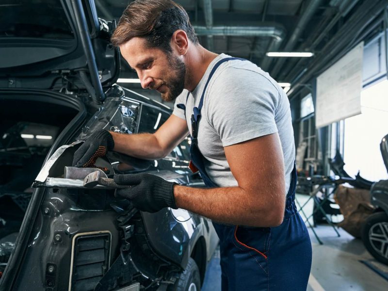 pleased-automotive-repairman-flattening-component-part-of-car.jpg